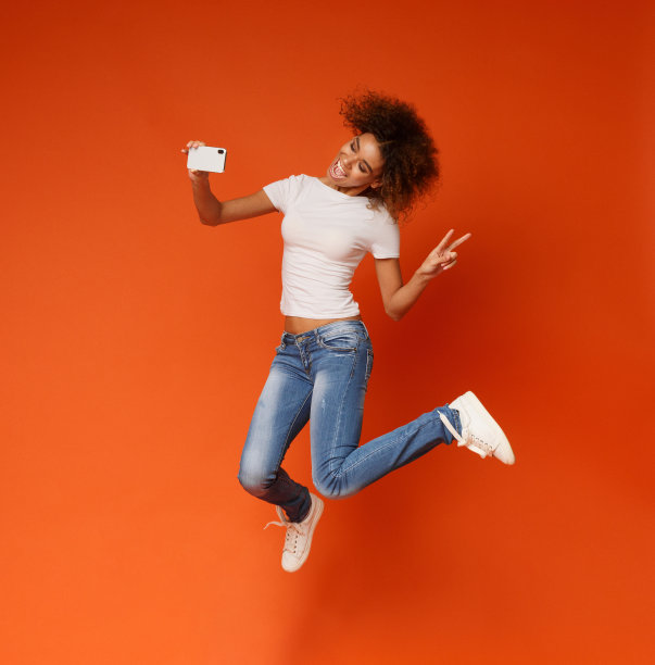 可爱的非裔美国女孩在智能手机上跳着自拍图片下载