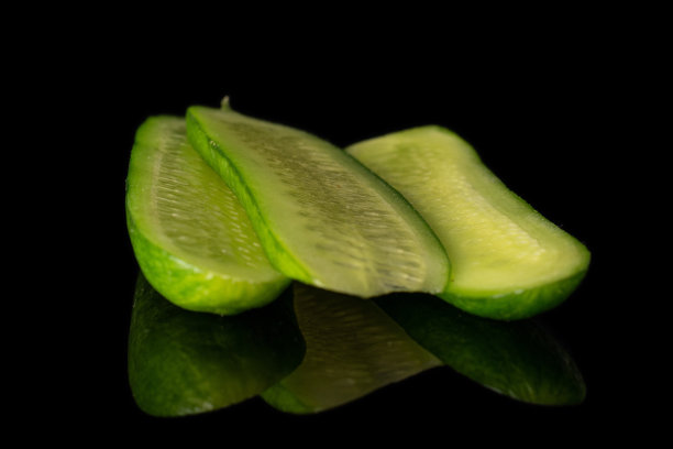 新鲜的小黄瓜，隔离在黑色玻璃上图片下载