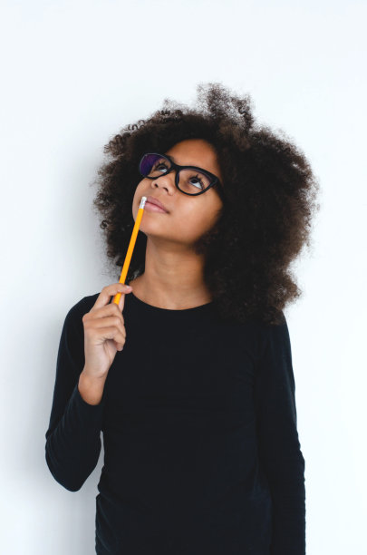 一个皮肤黝黑的女孩想了一会儿，把一支铅笔放在嘴唇上。图片下载