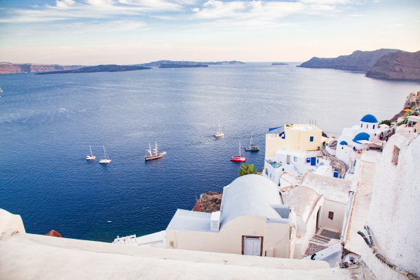 希腊圣托里尼岛上美丽的伊亚镇。位于爱琴海火山口的传统白色建筑和带有蓝色圆顶的希腊东正教教堂。景区旅游的背景图片下载