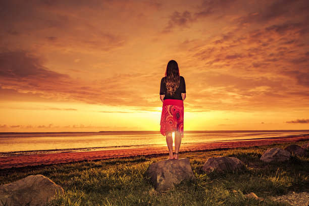 穿着红裙子的女人在海边欣赏日落图片下载