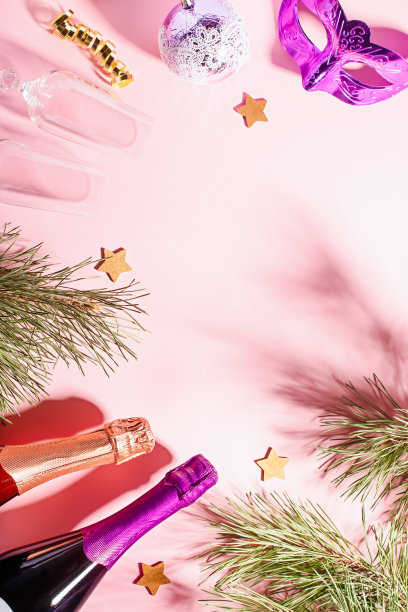 香槟酒瓶，葡萄酒杯与五彩纸屑，灯和金色的装饰品在淡粉色的背景，圣诞贺卡图片下载