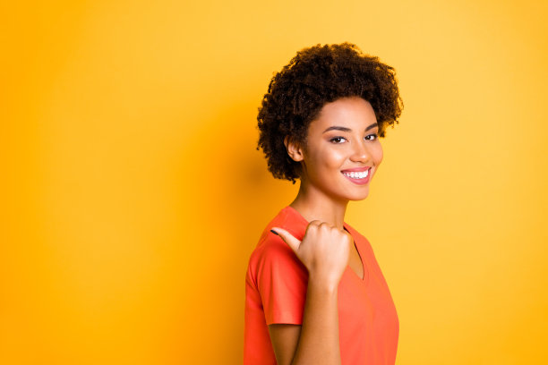 图片是一个活泼迷人的可爱迷人的小女孩指着购物中心的销售，她的拇指在鲜艳的颜色背景上被孤立图片下载