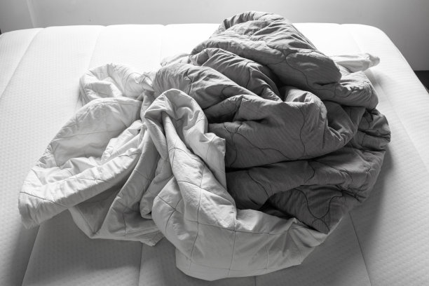 白色床上的灰色和白色皱巴巴的床单，特写，选择性聚焦，卧室清洁概念，黑白色调图片下载