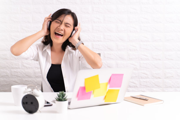 在办公室戴着耳机听音乐的快乐女人图片下载