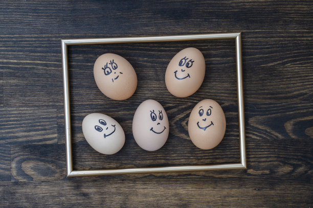图片的金色框架和许多有趣的鸡蛋微笑在黑暗的木墙背景。鸡蛋家庭情感面部肖像。概念有趣的食物图片下载
