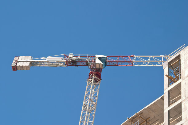 在蓝天的映衬下，一座塔吊和一座在建建筑的形象图片下载