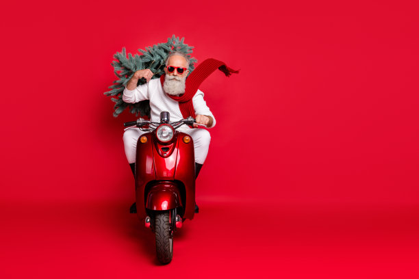 严肃的退休男子的全长照片扛杉树驾驶自行车有眼镜戴眼镜穿白色毛衣裤子靴子孤立在红色背景图片下载