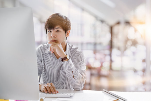 这是一个严肃的亚洲商人在共同工作空间里思考和专注于打字的照片。Man笔记本电脑工作概念图片下载