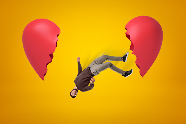 在黄色的背景上，穿着休闲衣服的年轻人在两颗破碎的心之间坠落图片下载