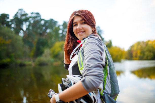 照片的快乐女人与背包和自行车头盔图片下载