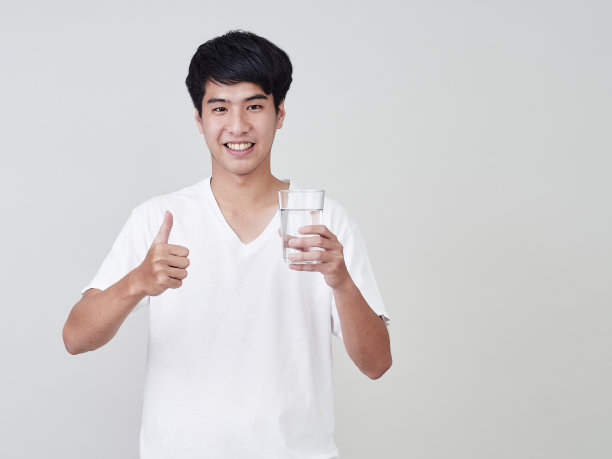 年轻的亚洲男人微笑着举着水杯在白色的背景。图片下载