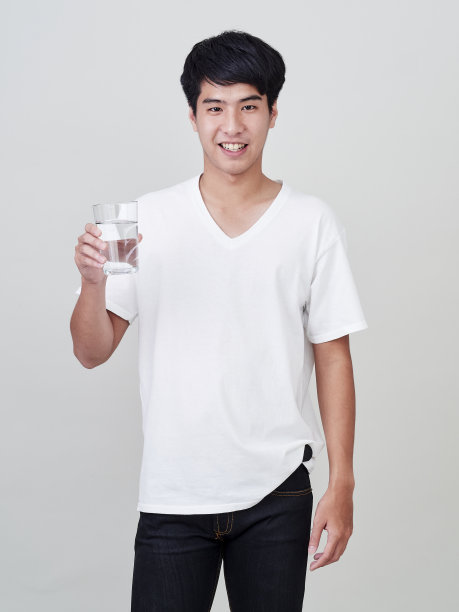 年轻的亚洲男人微笑着举着水杯在白色的背景。图片下载
