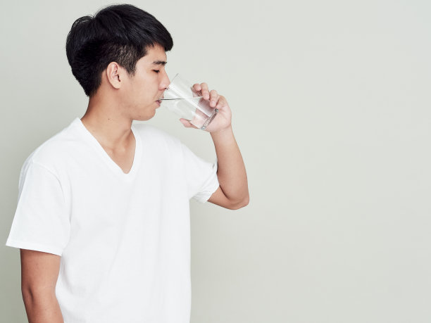 年轻人在喝水。孤立的工作室肖像上的白色。图片下载