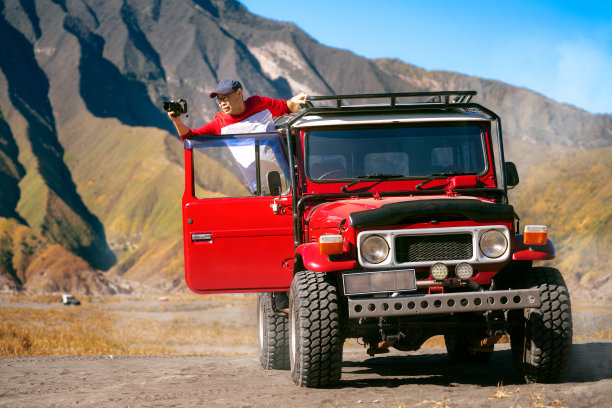 游客坐上一辆老式的越野汽车和Bromo山拍照图片下载