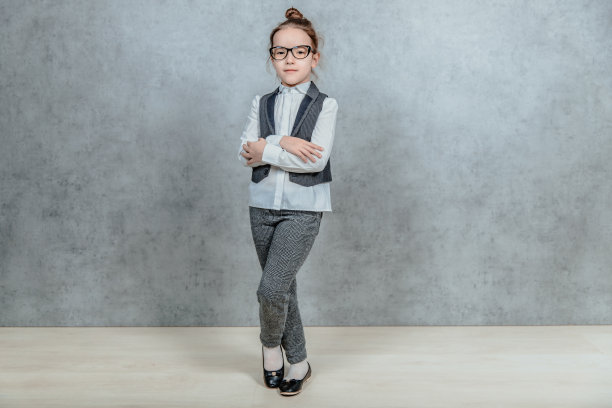 年轻的女商人站在灰色的背景上。在这期间，她把他的手放在他的背上。图片下载