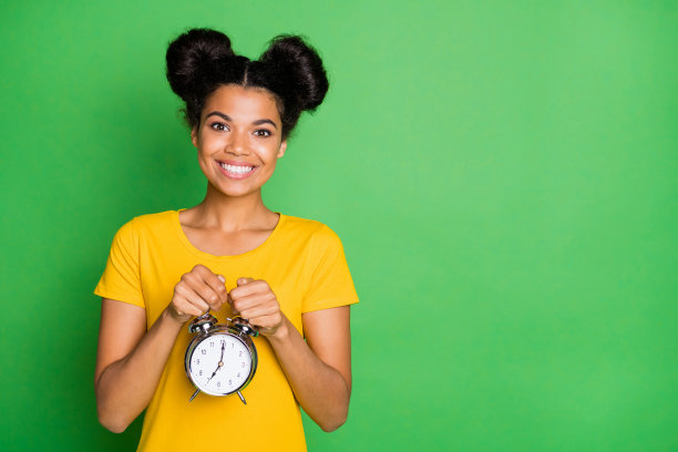 令人惊异的黑皮肤女士拿着大金属闹钟的照片推荐使用的人谁几乎起床早上穿休闲黄色t恤孤立的绿色背景图片下载