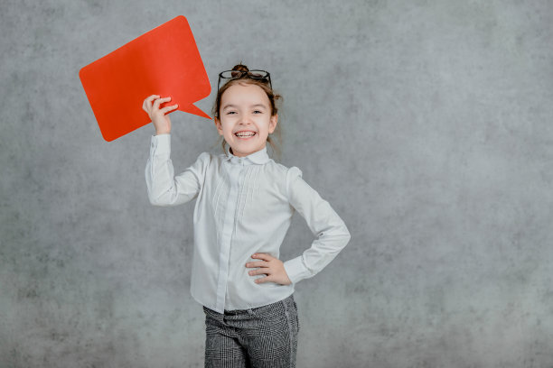 可爱的宝贝体贴的女孩，双手呈红色矩形。灰色的背景。图片下载