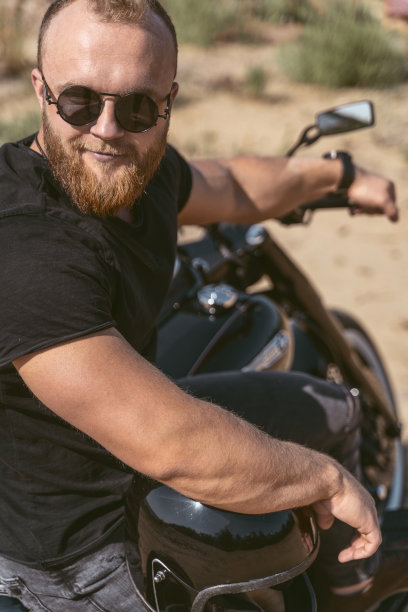 一个英俊的运动型摩托车手坐在他的自行车上的肖像图片下载