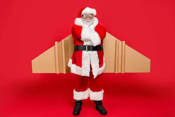 认真的酷的潮人圣诞老人的全身照片准备匆忙送礼物飞行在涡轮加速卡片板工艺翅膀戴帽子帽子裤子靴子孤立在红色的背景图片下载