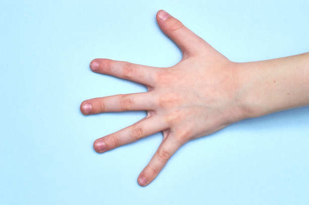 在蓝色的纸背景上，孩子的手所显示的手掌符号图片下载