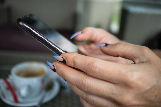 一个修过指甲的女人手里拿着智能手机图片下载