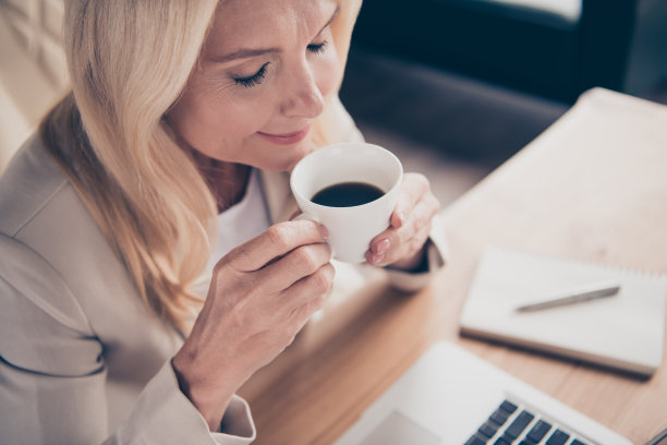 照片的金发愉快积极冷静宁静的企业家享受咖啡的味道，休息时在工作图片下载