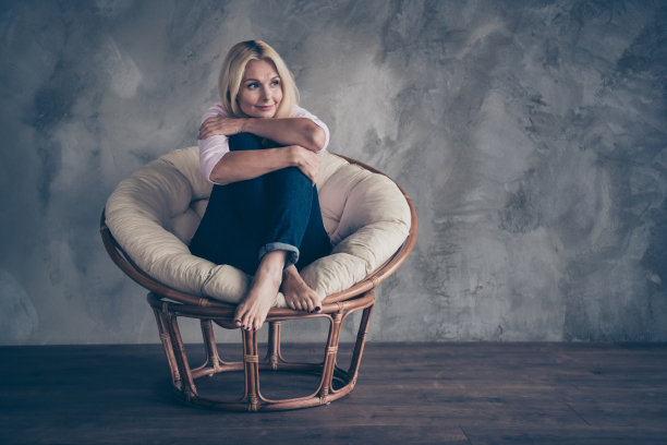 全身照片的和平梦幻的中年妇女坐在现代酒店柳条椅梦想她未来的周末穿柔和的颜色的牛仔室内图片下载