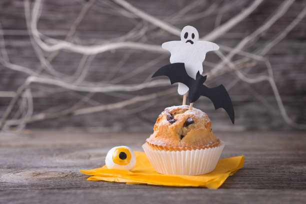 万圣节的纸杯蛋糕在桌子上装饰着蝙蝠，幽灵和眼睛。图片下载