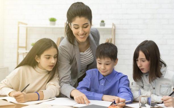 年轻的老师帮助孩子们一起做作业图片下载