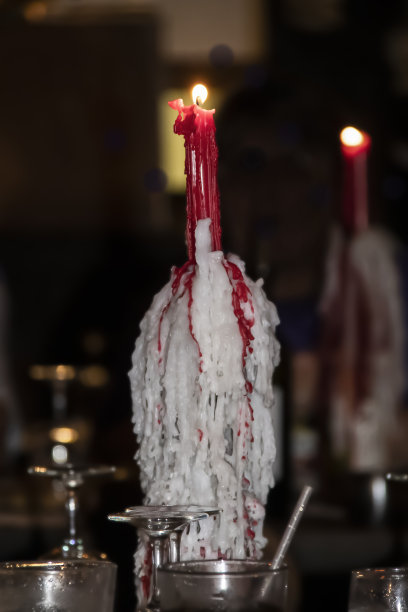 酒瓶烛台上覆盖着蜡，烛台上点燃的蜡烛，坐在吧台上映着镜子图片下载