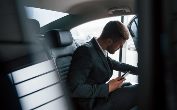 在见面地点。穿着公务服的商人有电话时坐在车的后面图片下载