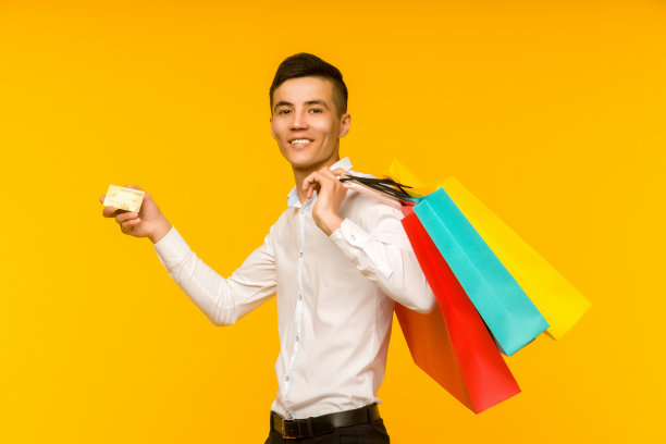 年轻的亚洲男子展示他的购物袋和信用卡图片下载