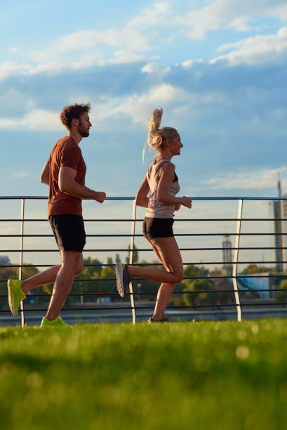 现代女人和男人在河边的城市环境中慢跑/锻炼。图片下载