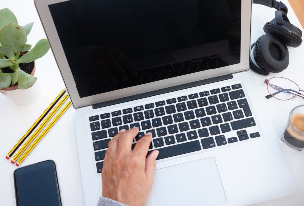 用笔记本电脑工作的高级女性的手。白色的桌子上。喝点咖啡休息一下。选择户外办公室。把手机和耳机放在身边图片下载