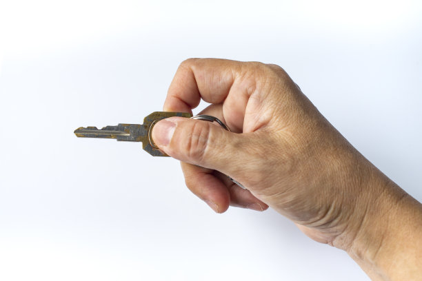 女人的右手使用钥匙在白色背景下锁或解锁，近距离微距拍摄，选择性聚焦，安全概念图片下载