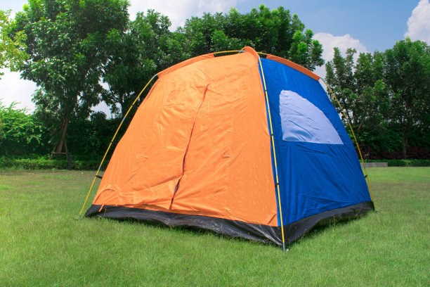 橙色和蓝色家庭露营帐篷没有雨蝇设置在绿色公园营地。图片下载