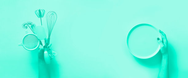 烘焙平。女性手握着盘子，厨房工具，筛子，擀面杖，抹刀和树枝在薄荷色背景上。时尚的绿色和绿松石色。图片下载