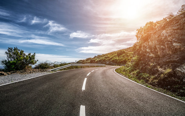 在一个阳光明媚的夏日，在明亮的夕阳下，空长的路图片下载