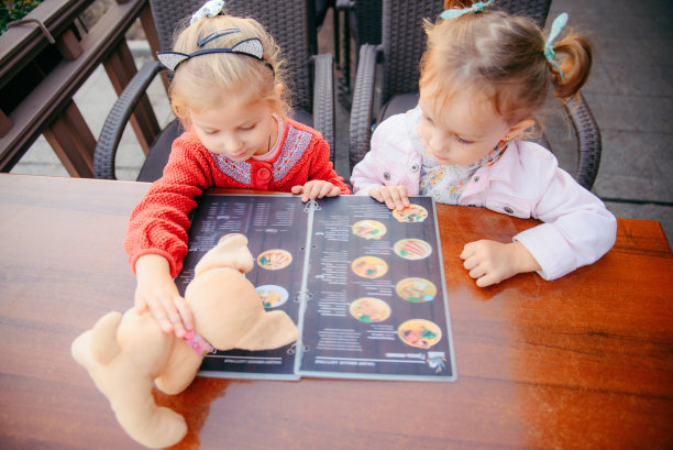 小女孩坐在咖啡馆里选择菜单上的食物生活方式图片下载