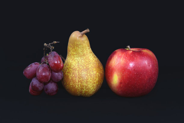 健康的生红葡萄、梨和红苹果在黑色的背景下排成一排图片下载
