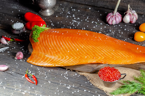 漂亮的烟熏红或白鱼片放在一个古老的乡村砧板和桌子上，绳子、柠檬片和酸橙片被整块切成圆形，周围，绿色的光图片下载