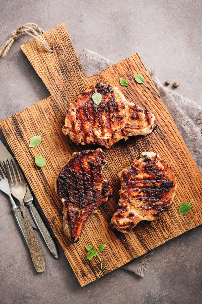 在砧板上烤猪肉片，俯视图，平铺，复制空间。烧烤猪肉。图片下载