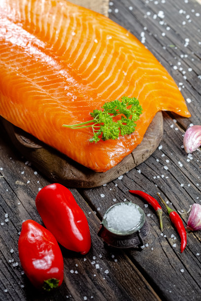 漂亮的烟熏红或白鱼片放在一个古老的乡村砧板和桌子上，绳子、柠檬片和酸橙片被整块切成圆形，周围，绿色的光图片下载