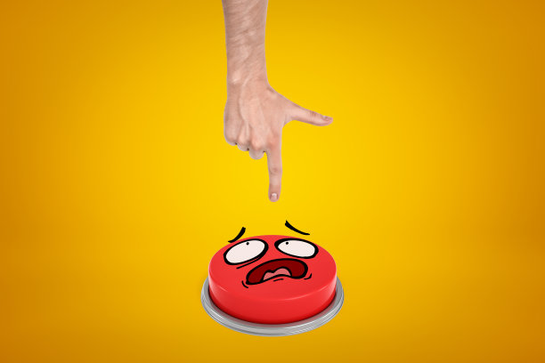 农作物视图的手从上面出现准备按大红色按钮与卡通脸在黄色的背景。图片下载