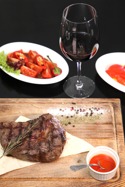 在木板上切成块的中等烘烤的牛排，加上调味汁和调味料。美味的牛排。图片下载
