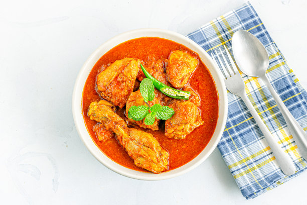印度咖喱鸡在一个碗，叉子和勺子在白色的背景图片下载