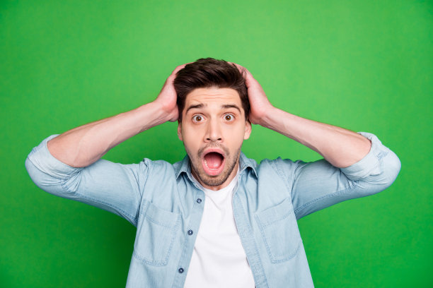 这是一张疯狂的恐怖的男人在知道世界上最坏的消息后抱着他的头的照片，鬃毛被孤立在绿色生动的背景上图片下载