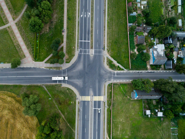 俯视图柏油路，在一个阳光明媚的日子十字路口的村庄。运输枢纽的航拍照片图片下载