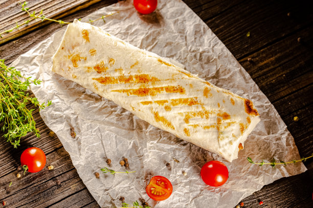 躺在一个老式的木桌上，在砧板上，多汁的烤肉沙瓦玛，有肉块，蔬菜，酱汁，深色的背景，特写，广角，全切，整个，樱桃番茄上图片下载